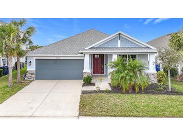 One-story home with gray siding, red door, and landscaping at 5629 Maidenstone Way, Palmetto, FL 34221