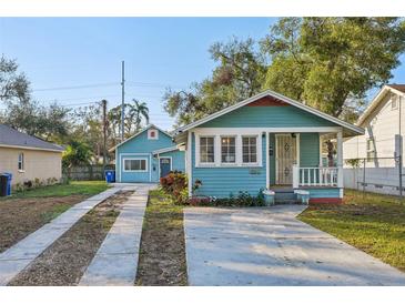 Charming blue bungalow featuring a quaint front porch and a long driveway to the garage at 612 12Th S Ave, St Petersburg, FL 33701