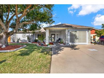 Single-story home with landscaped yard, driveway, and mature tree at 9445 Barnstead Ln, Port Richey, FL 34668