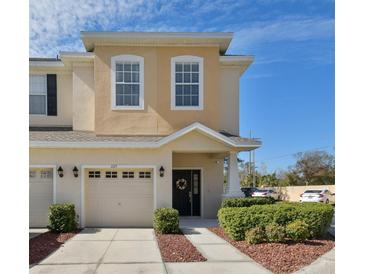 Tan two-story townhome with a two-car garage and landscaping at 1115 Andrew Aviles Cir, Tampa, FL 33619