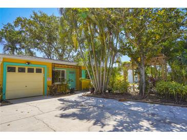 Charming yellow home featuring colorful trim, well-maintained landscaping, and a private driveway at 9665 2Nd N St, St Petersburg, FL 33702