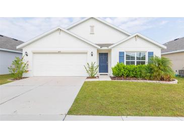 White house with blue shutters, two-car garage, and landscaped lawn at 1024 Golden Shiner Ave, Ruskin, FL 33570