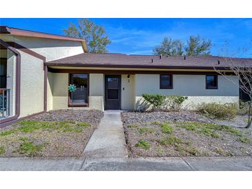 Front view of a light-yellow single-story home with a brown roof and walkway at 1311 Powderpuff Dr # 1003, Dunedin, FL 34698