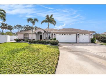 Beautiful home with 3-car garage, lush landscaping, and palm trees at 9203 Sea Oaks Ct, Seminole, FL 33776