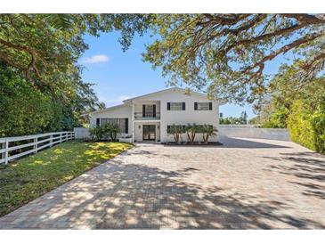 Two-story home with a brick paver driveway and a white picket fence at 1 Gallinule Pl, Belleair, FL 33756