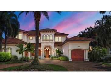 Stunning two-story Mediterranean-style home with lush landscaping, tile roof, and a paver driveway at 1097 Eden Isle Ne Dr, St Petersburg, FL 33704