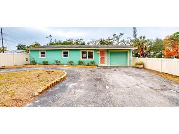 Charming light teal single story home with a circular driveway and white vinyl fence at 1130 Queen N St, St Petersburg, FL 33713