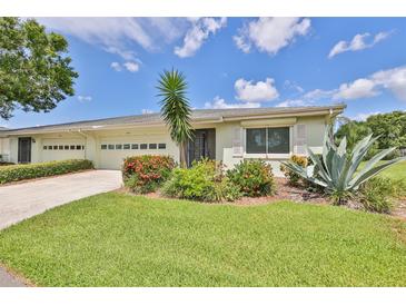 Updated exterior of a light-green single-story home with a two-car garage and nicely landscaped yard at 2421 Lancaster Dr, Sun City Center, FL 33573