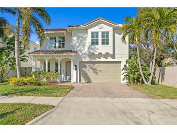 Two-story home with white stucco exterior, red tile roof, an attached two car garage, and landscaped front yard at 3107 W Palmira Ave, Tampa, FL 33629