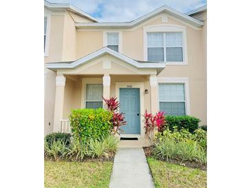 Two-story townhome with light beige exterior, landscaping, and teal door at 5010 Cactus Needle Ln, Wesley Chapel, FL 33544