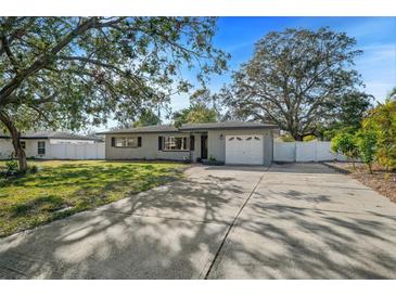 Gray house with a white garage door and a spacious driveway, surrounded by lush green landscaping at 1720 Hampton Ln, Clearwater, FL 33756