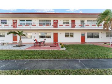 Red and white condo building with a well-maintained lawn and patio at 1950 58Th N Ave # 9, St Petersburg, FL 33714