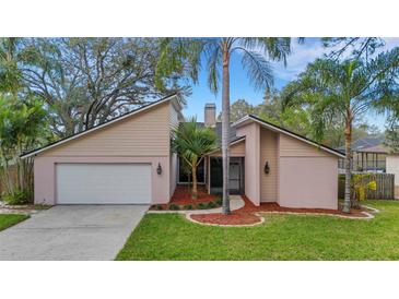 Tan house with white garage door, landscaping, and palm trees at 2826 Kavalier Dr, Palm Harbor, FL 34684