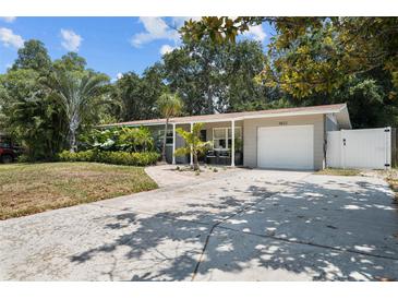 Updated home with a large front yard, driveway, and white fence at 4822 W Bay Court Ave, Tampa, FL 33611