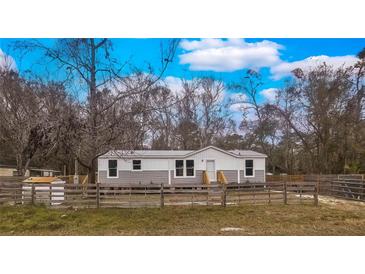Newly built manufactured home with gray siding, wooden steps, and fenced yard at 13017 Manatee Ave, New Port Richey, FL 34654