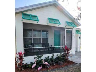 Charming home featuring a screened-in porch, turquoise door, and colorful landscaping at 301 E Grace St, Punta Gorda, FL 33950