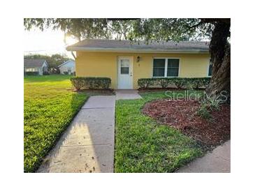 Exterior view of a yellow single-story home with well-maintained landscaping at 401 Dorchester Pl # 62, Sun City Center, FL 33573
