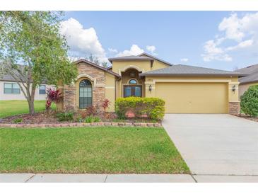 Charming single-Gathering home featuring well-maintained landscaping, a stone-accented facade, and an attached two-car garage at 6722 Boulder Run Loop, Wesley Chapel, FL 33545