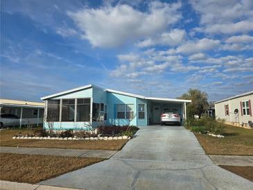 Light blue single-wide manufactured home with carport and screened porch at 3841 Julie Dr, Wesley Chapel, FL 33543