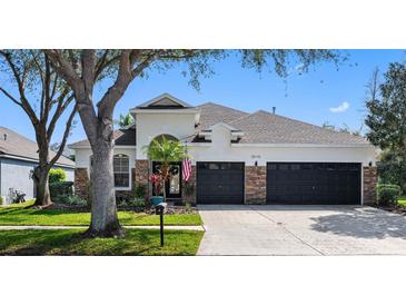 Charming single Gathering home featuring manicured landscaping, stone accents and a three-car garage at 15110 Shearcrest Dr, Lithia, FL 33547