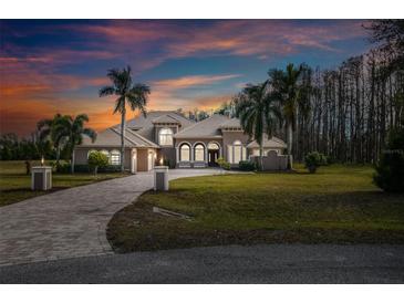 Stunning home exterior featuring lush landscaping and a paver driveway under a colorful sky at 17336 Ballmont Park Dr, Odessa, FL 33556