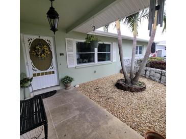 Front porch entry with white door, potted plants, and a small bench at 568 Seacrest Dr, Largo, FL 33771