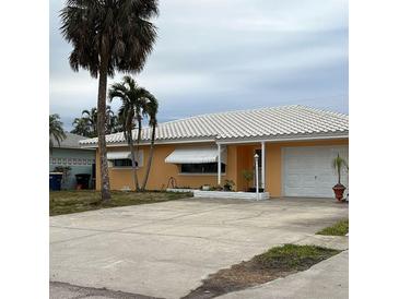 One-story house with a white roof, attached garage, and palm trees at 1019 Mandalay Ave, Clearwater Beach, FL 33767