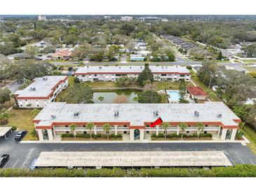 Aerial view of condo community showing building, pool, and surrounding landscape at 1750 Belleair Forest Dr # A15, Belleair, FL 33756