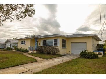 Ranch-style home with a yellow exterior, attached garage, and landscaped lawn at 1900 41St N St, St Petersburg, FL 33713