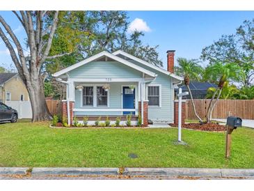 Charming bungalow featuring a cozy porch, light blue exterior, brick accents, and a well-manicured front yard at 705 W Kentucky Ave, Tampa, FL 33603