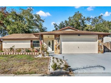 House exterior featuring stone accents, a two-car garage, and well-maintained landscaping at 1212 Markley Dr, Largo, FL 33770