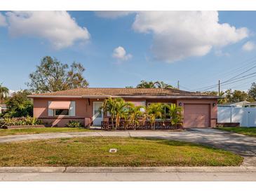 Ranch-style home with a pink exterior, driveway, and landscaping at 2351 Leslee Lake N Dr, St Petersburg, FL 33713