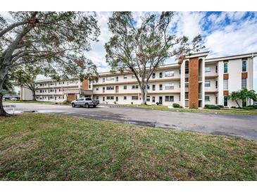 Three-story condo building featuring a mature tree, well-maintained landscaping and parking at 5880 38Th N Ave # 204, St Petersburg, FL 33710