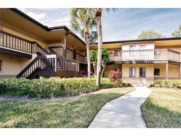 Exterior view of condo building with walkway, landscaping, and palm trees at 2679 Sabal Springs Cir # 102, Clearwater, FL 33761