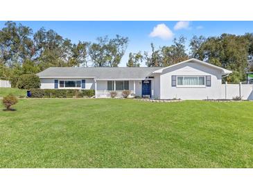 White brick ranch house with blue door, landscaped yard, and a spacious lawn at 36639 Jefferson Ave, Dade City, FL 33523