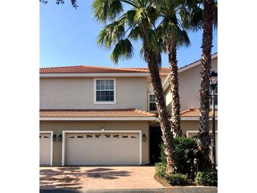 Tan two-story townhome with double garage and palm trees at 1314 Riserva Ln, Palm Harbor, FL 34683