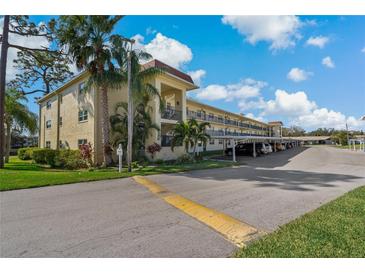 Well-maintained condo complex with assigned covered parking and mature landscaping on a sunny day at 1450 Heather Ridge Blvd # 305, Dunedin, FL 34698