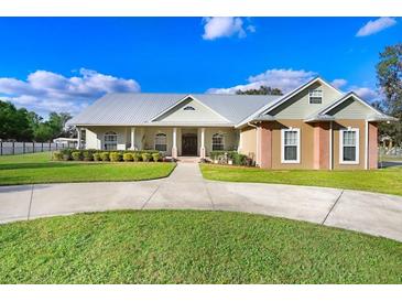 Charming home showcasing a manicured lawn and circular driveway, surrounded by lush landscaping at 1702 W Knights Griffin Rd, Plant City, FL 33565