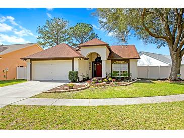 Charming single-story home features a two-car garage and a well-maintained front yard with flower beds at 18529 Otterwood Ave, Tampa, FL 33647