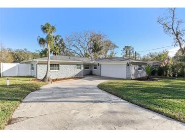 Gray brick ranch house with a two-car garage and landscaped yard at 18615 Yocam Ave, Lutz, FL 33549