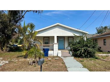 Charming bungalow with a light blue front door, front porch, and landscaped yard at 502 E Cluster Ave, Tampa, FL 33604