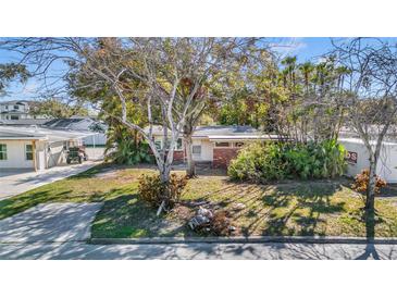 Charming single-story home with a brick facade, mature trees, and a well-maintained lawn at 90 Huron Ave, Tampa, FL 33606