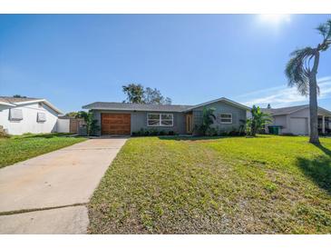 Updated home exterior boasts a modern gray color, wood garage door, and landscaped lawn at 9893 111Th St, Seminole, FL 33772