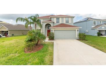 Two-story house with light gray siding, red door, and a large driveway at 11601 Mansfield Point Dr, Riverview, FL 33569