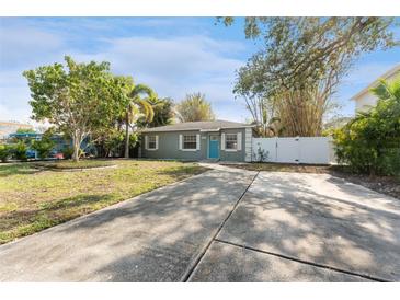 Gray house with blue door, landscaped yard, and a long driveway at 4724 W Lawn Ave, Tampa, FL 33611