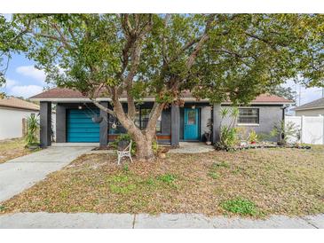 Gray house with teal door, mature tree, and landscaping at 1232 Calamondin Dr, Holiday, FL 34691