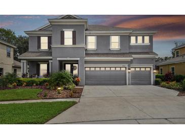 Two-story house with gray siding, three car garage, and landscaped front yard at 19322 Autumn Chase Ct, Land O Lakes, FL 34638