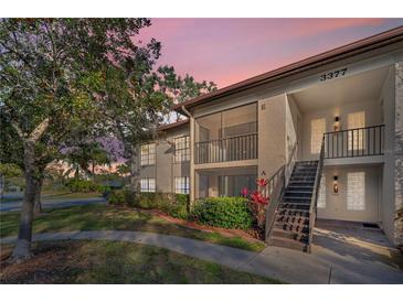 Two-story condo building with a staircase leading to the upper units and well-maintained landscaping at 3377 Crystal E Ct # E, Palm Harbor, FL 34685