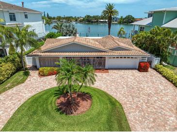 Aerial view of waterfront home with circular driveway, landscaping, and private dock at 476 Harbor S Dr, Indian Rocks Beach, FL 33785