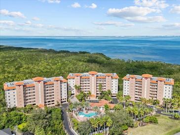 Stunning aerial view of condo buildings, lush greenery, ocean views, and a sparkling community pool at 12033 Gandy N Blvd # 145, St Petersburg, FL 33702